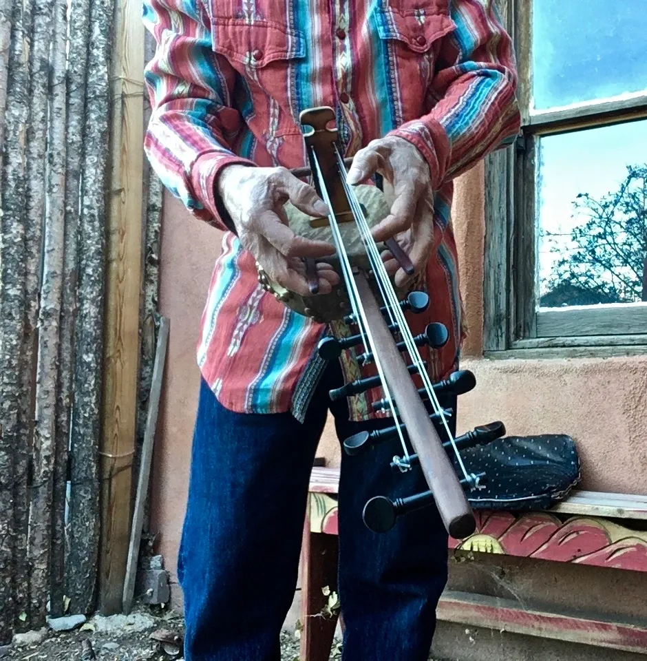 A man playing Ngoma, an African musical instrument, in front of a house.