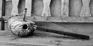 A black and white photo of a musical instrument, namely a Kalimba, on a wooden bench.