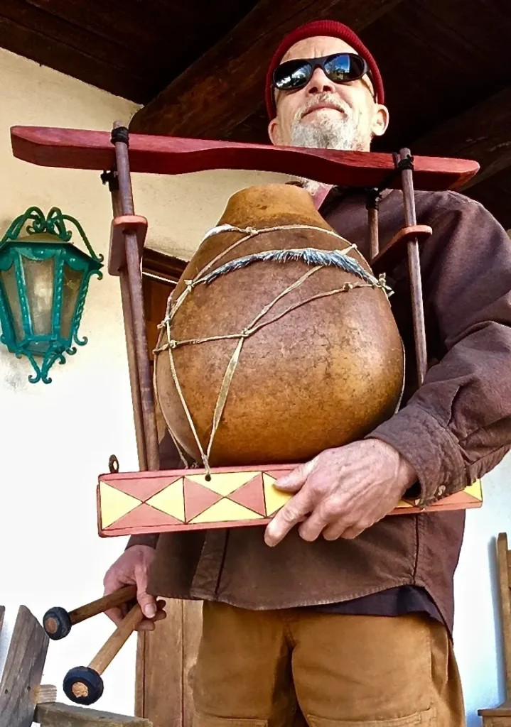 A man in sunglasses holding a wooden lamellaphone drum.