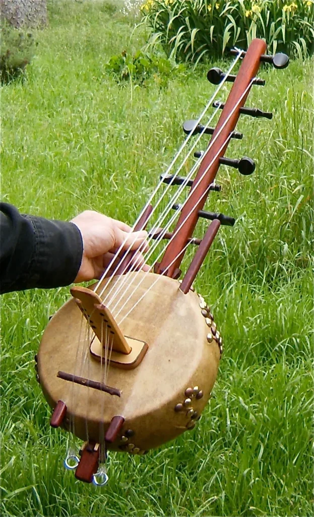 A person playing a Ngoma, an African wooden instrument, in the grass.