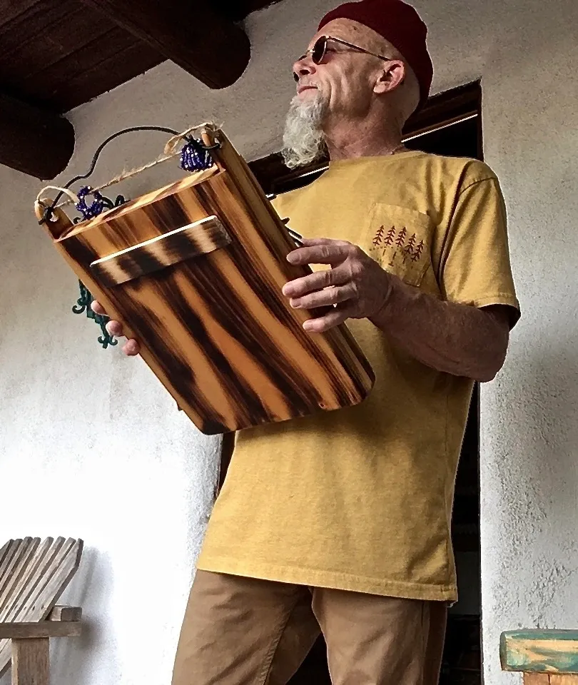 A Ngoma musician with a beard holding a wooden box.