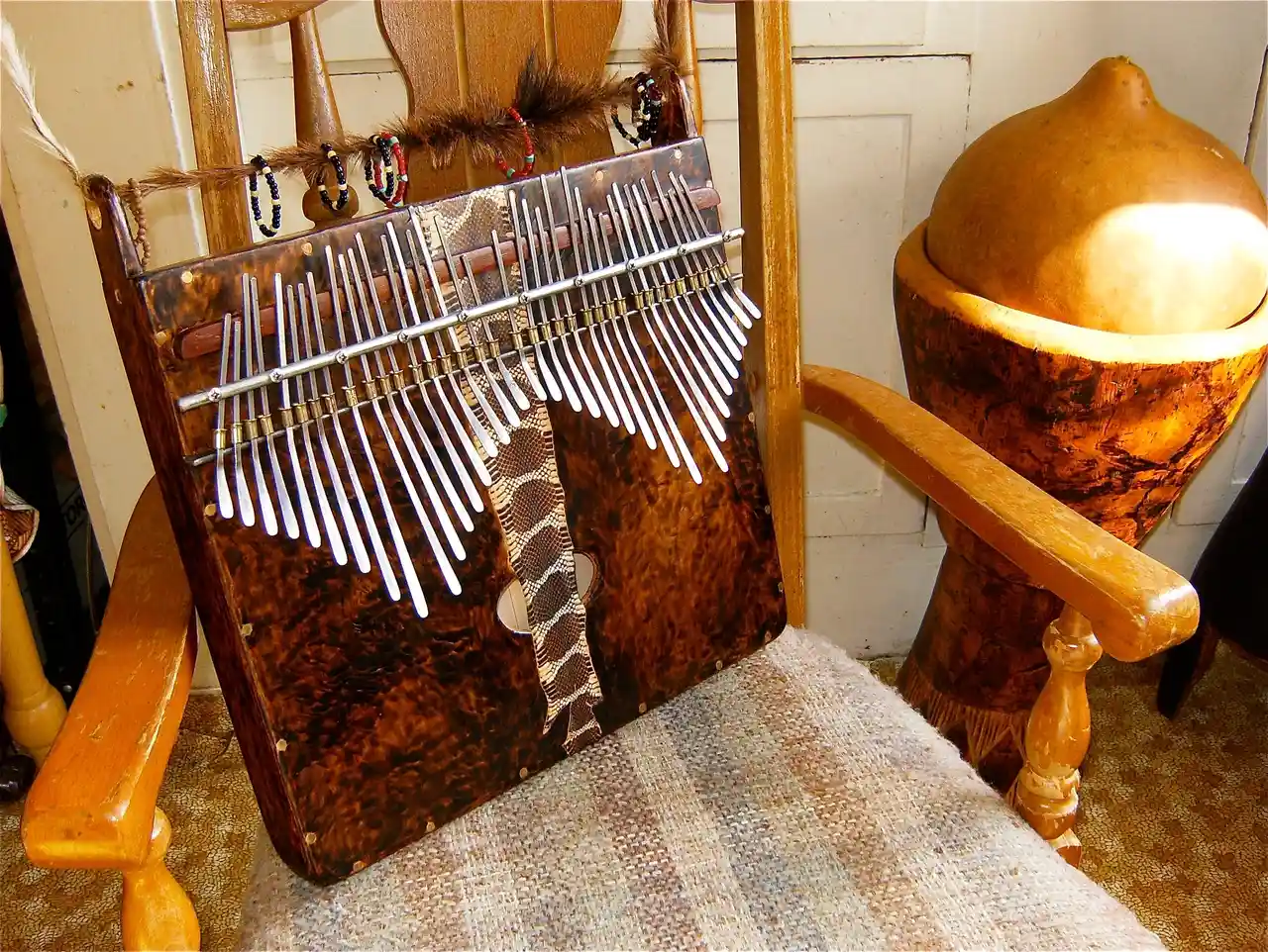 A wooden chair with a musical instrument on it, specifically a Kongoma.