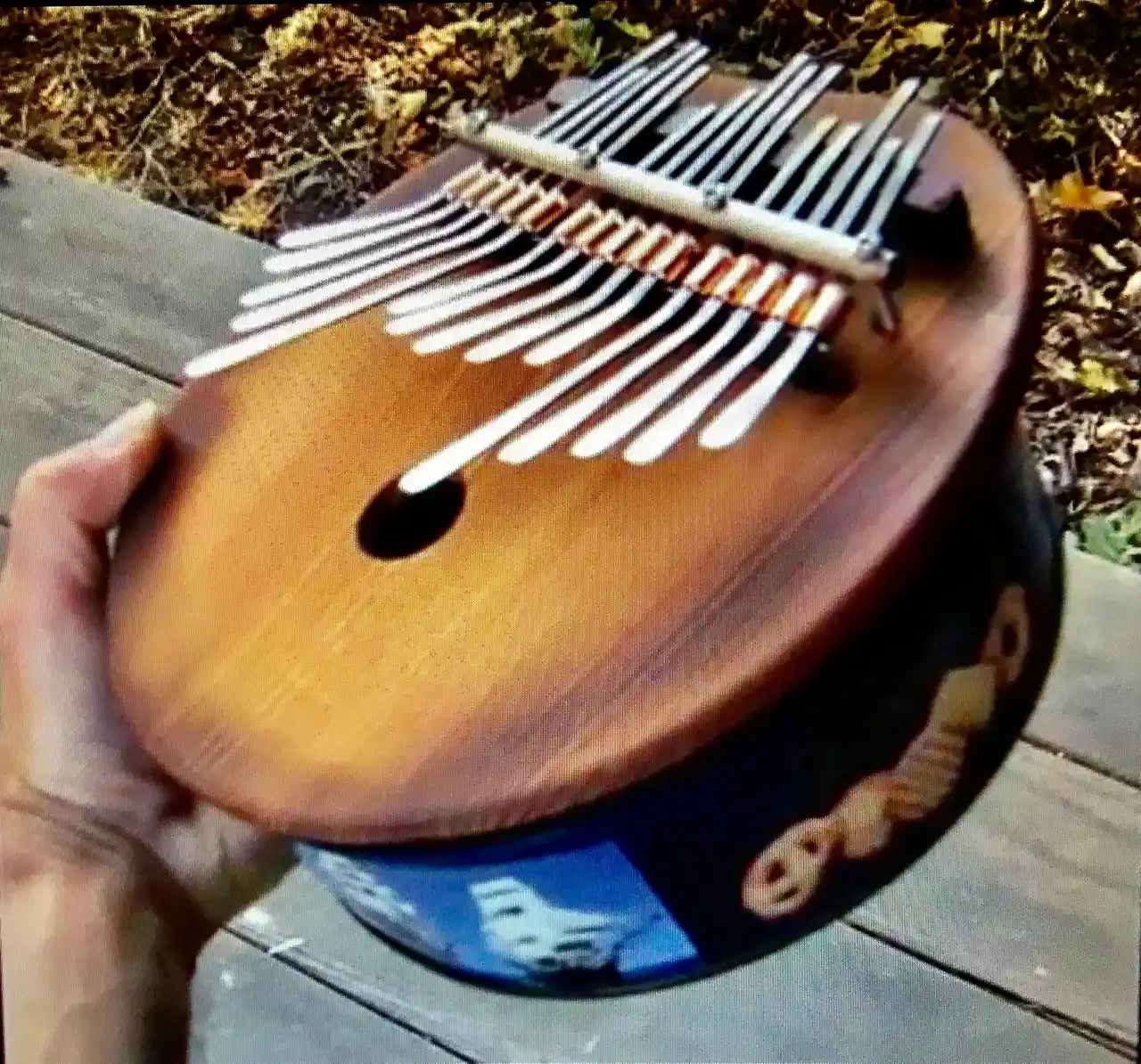 A person is holding a Ngoma, a wooden instrument used in African music, with spoons in it.