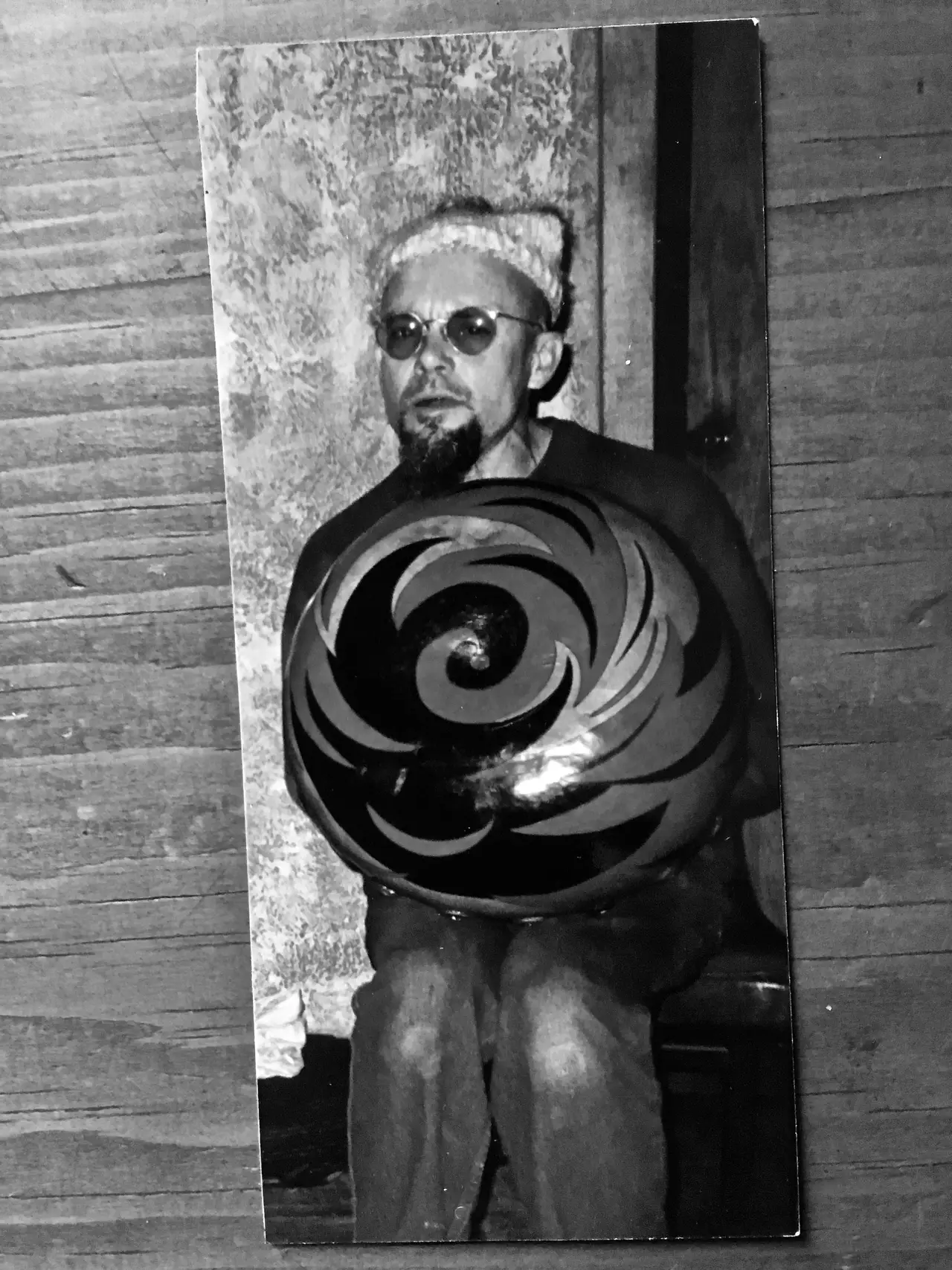 A black and white photo of a man holding a bowling ball with a Ngoma drum next to him.