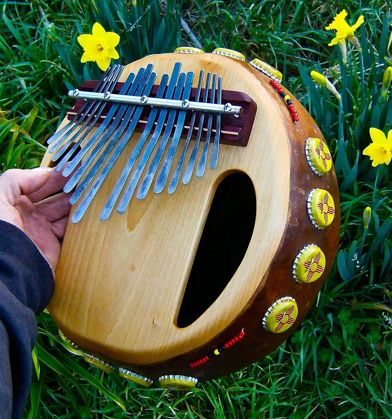 A person holding an African harp in the grass.