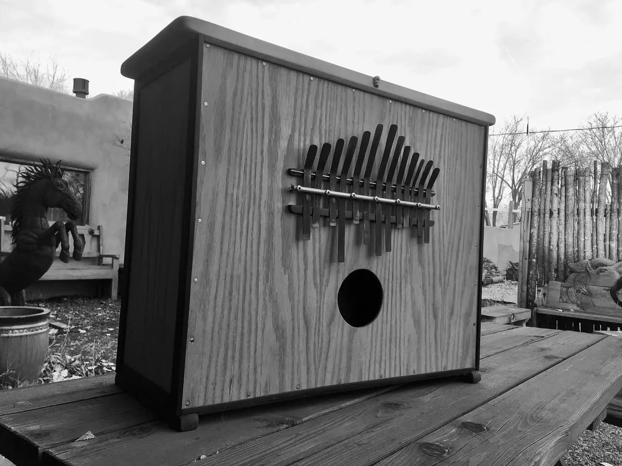 A black and white photo of a wooden box on a table, featuring the Kalimba.