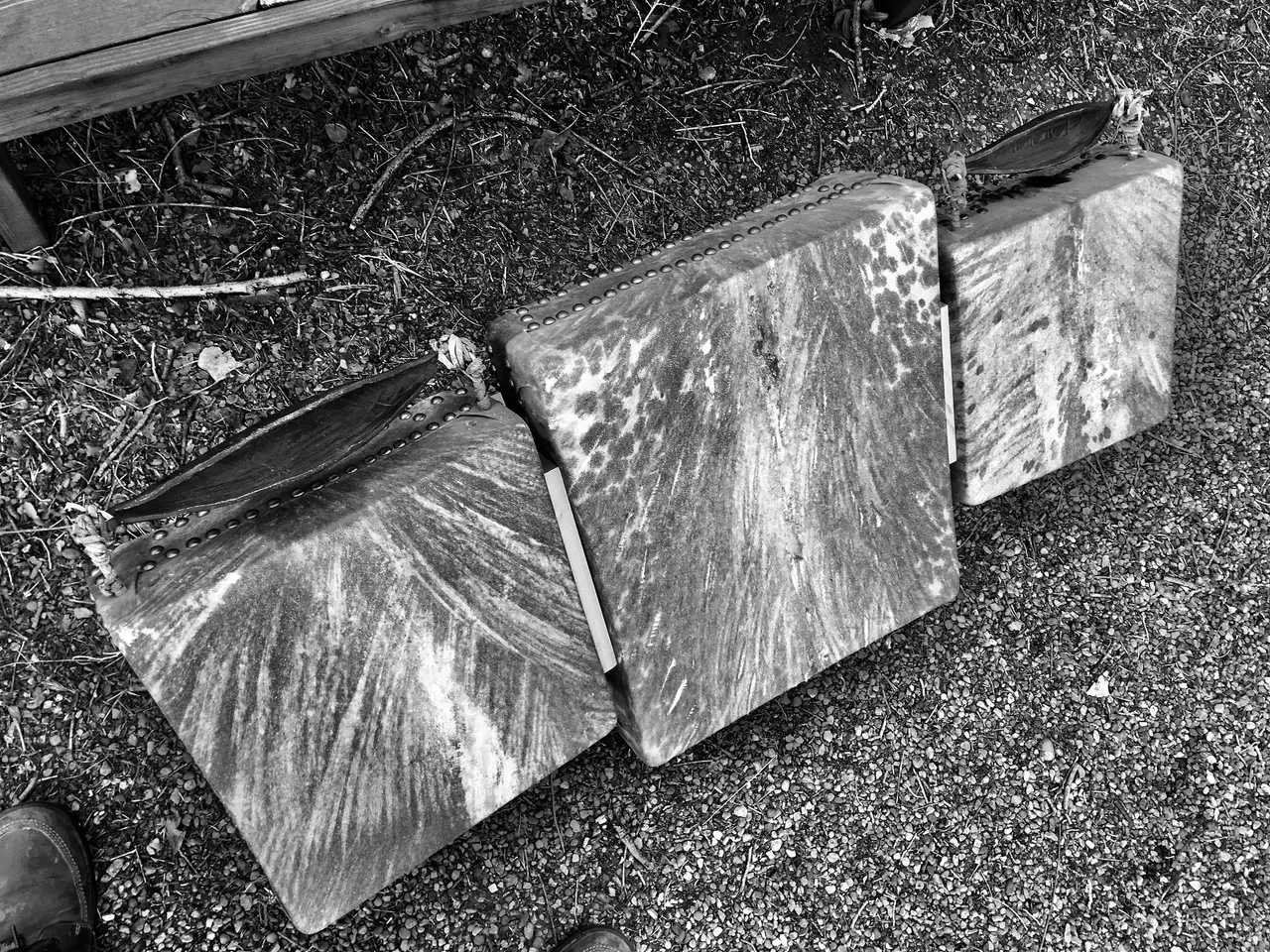 A black and white photo of three wooden boards on the ground, resembling the keys of a Kalimba.