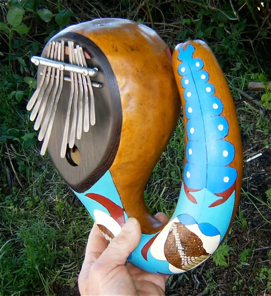 A person is holding a wooden ukulele, commonly known as Ngoma, in their hand.