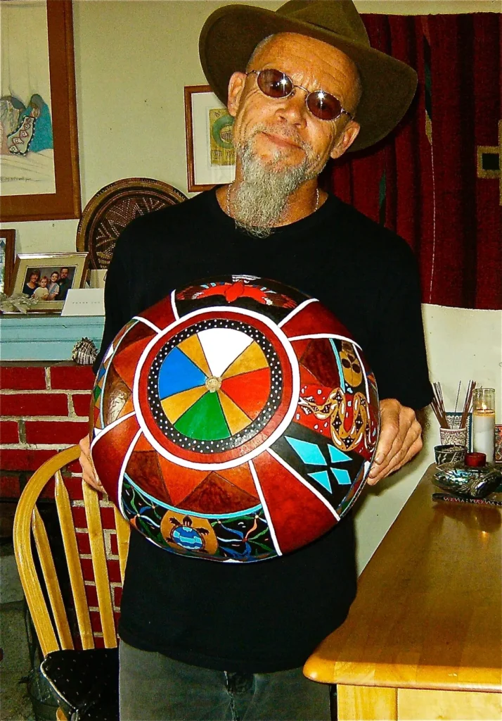 A man wearing a hat holding a colorful frisbee while enjoying Ngoma, African music.