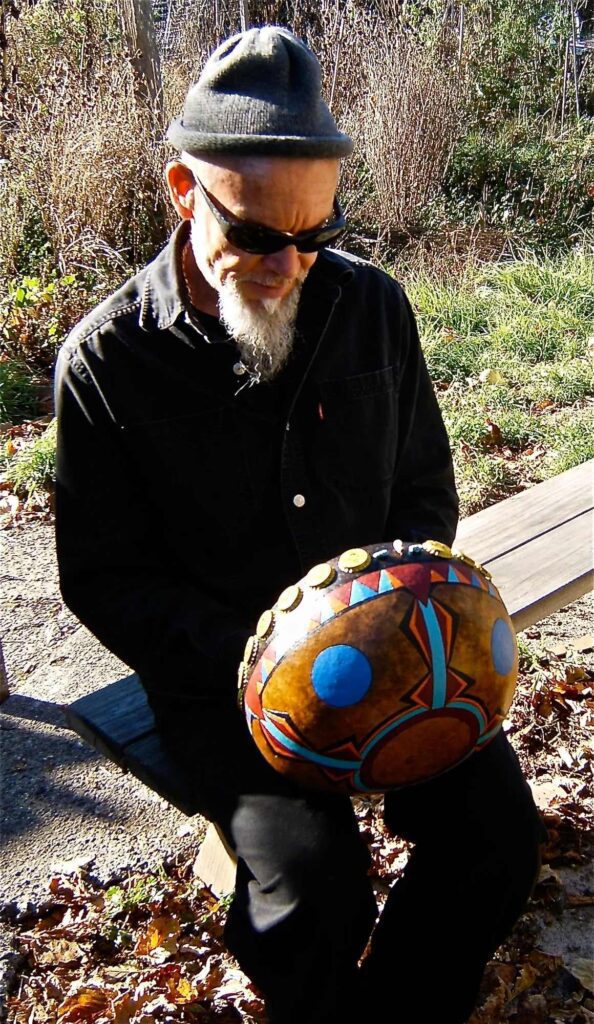 A man sitting on a bench holding an African Ngoma drum.