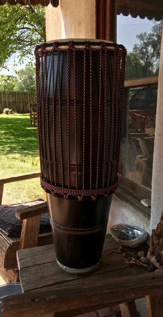 A large black Kongoma drum sitting on a wooden table.