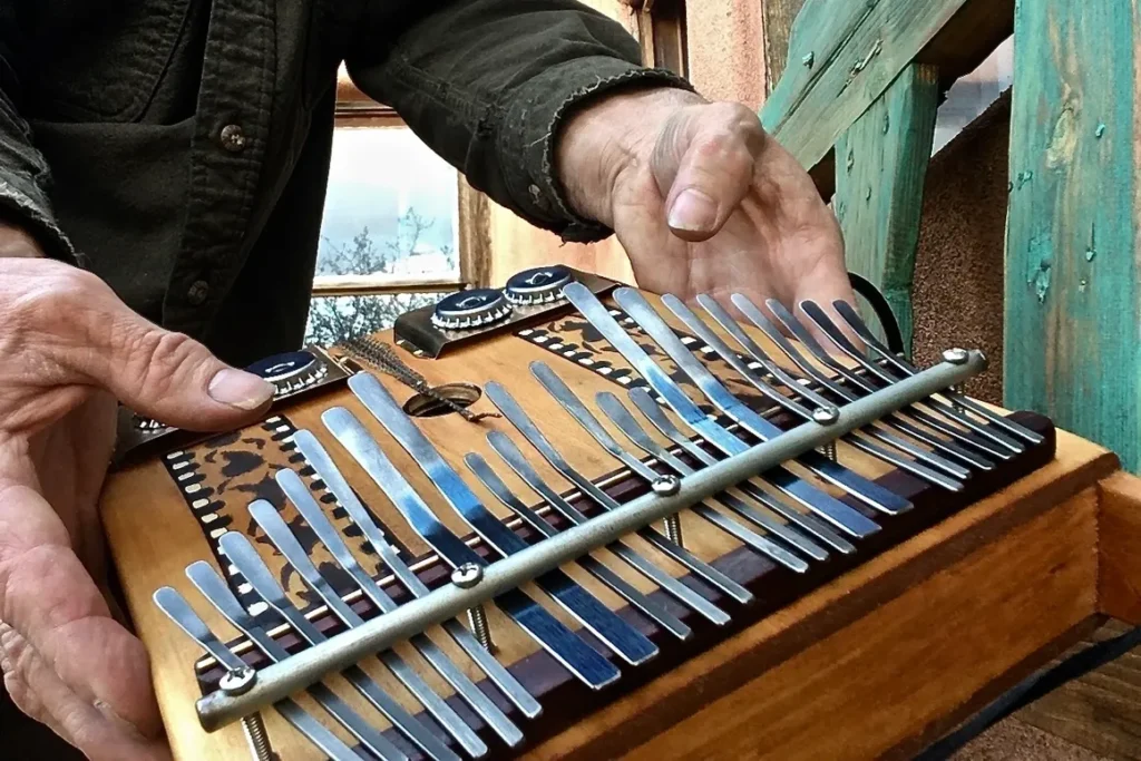 A man is holding a Lamellaphone, a wooden instrument with metal blades.