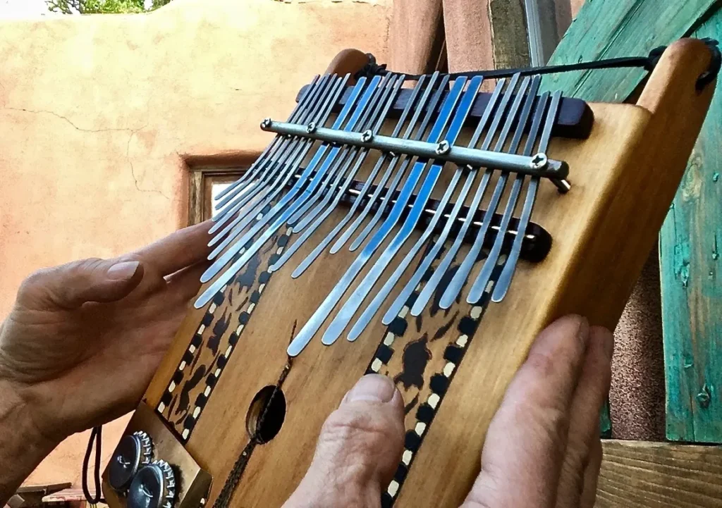 A person is holding a Lamellaphone, a wooden instrument with a lot of tines.