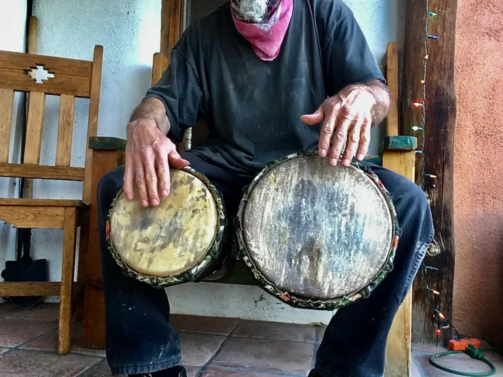 A man sitting on a bench playing an Ilimba drum.