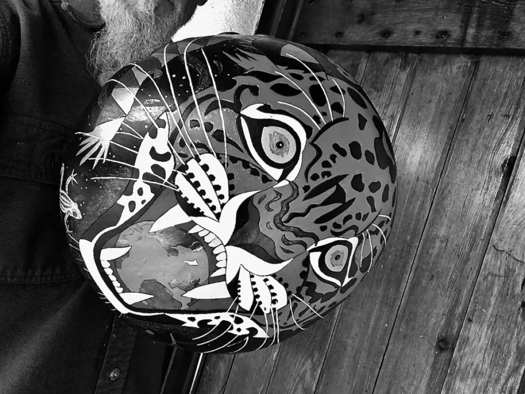 A black and white photo of a man with a tiger on his head, showcasing the unique combination of African harps and Ilimba.