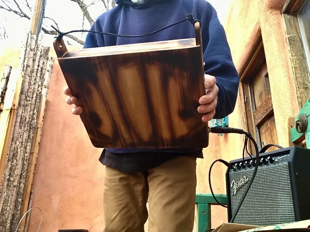 A man holding a Kongoma in a wooden box.