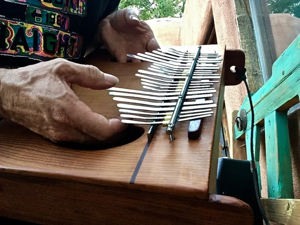 A man is playing a lamellaphone instrument with a lot of tines.