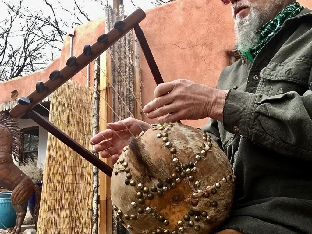 A man with a beard is playing an African drum.