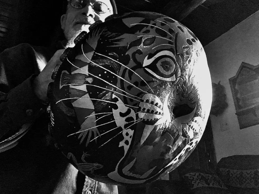 A black and white photo of a man holding an Ilimba mask.