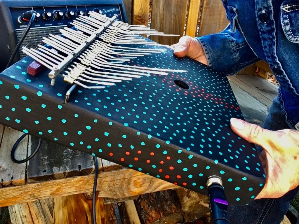 A man holding a musical instrument with a polka dot pattern known as Kongoma.