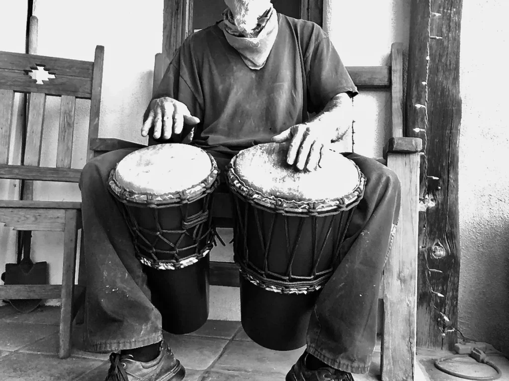 A man sitting on a chair playing an African harps.