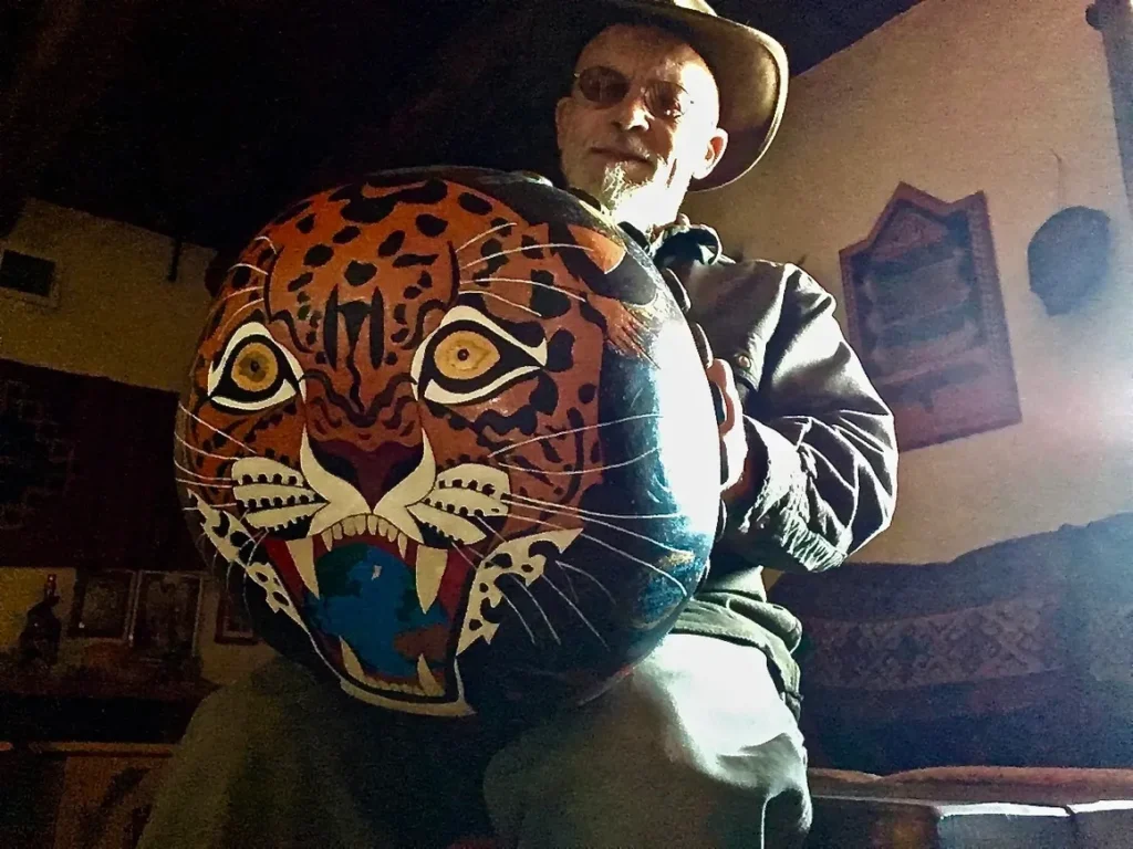 A man in a cowboy hat holding an Ilimba drum.