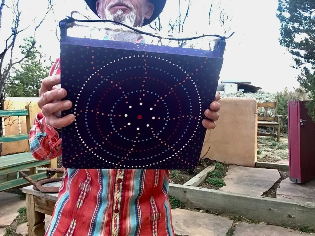 A man in a hat holding up a purple box with a Kongoma.