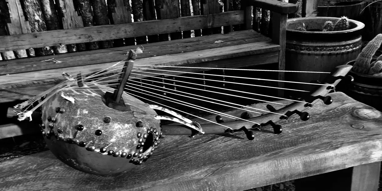 A black and white photo of a harp on a wooden bench inspired by African music.