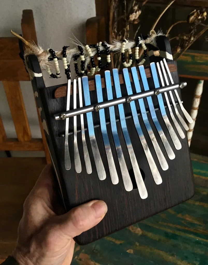 A person holding a Ngoma, a wooden accordion commonly used in African music, with blue and silver tines.