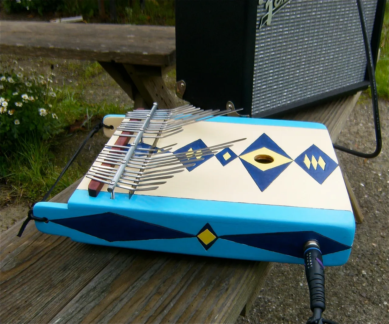 A blue and white lamellaphone sitting on a wooden bench.