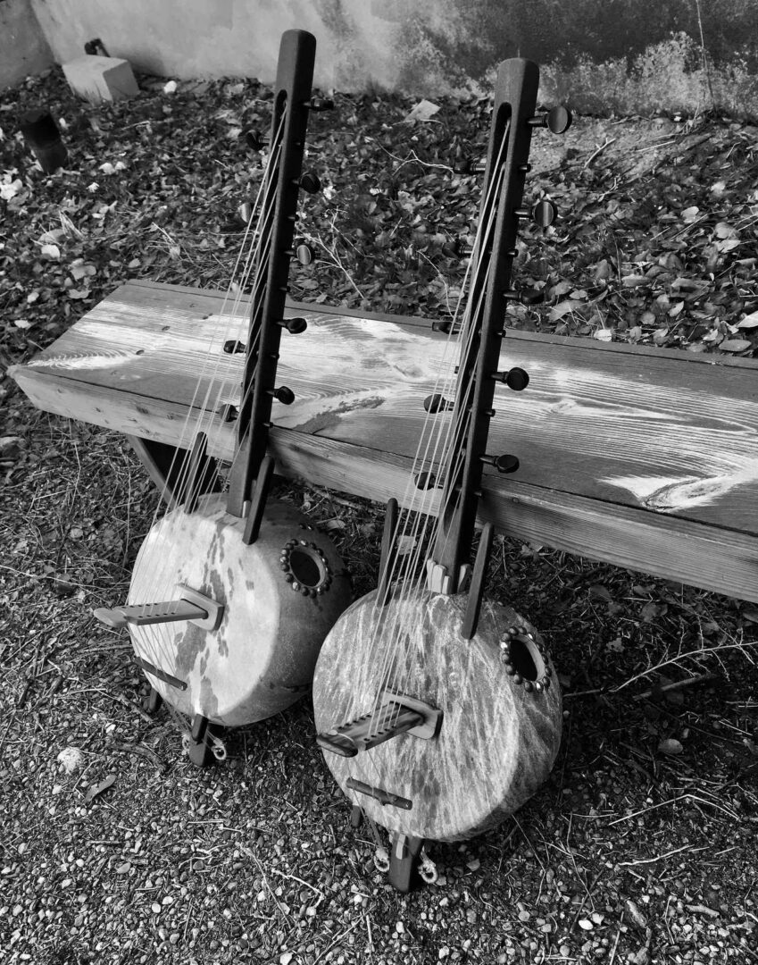 Two banjos, one Ngoma, sitting on a wooden bench.