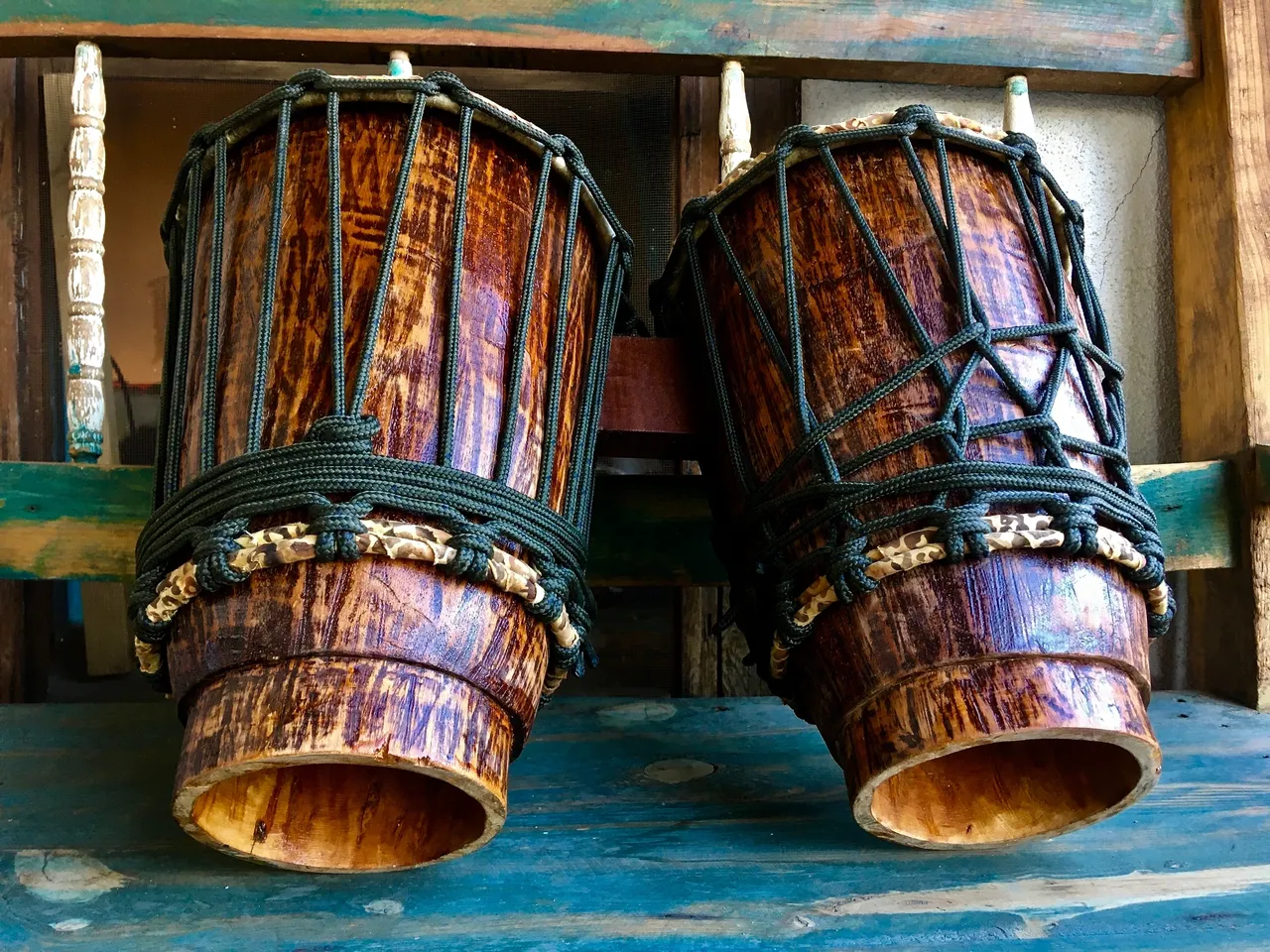 Two wooden djembes, African harps, sitting on a wooden table.