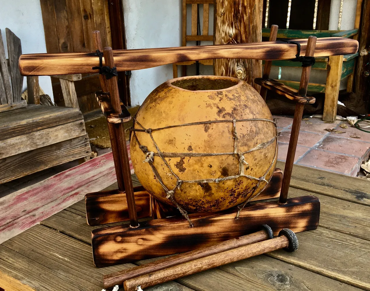 A wooden bowl with a wooden handle on it, resembling a gourd instrument.