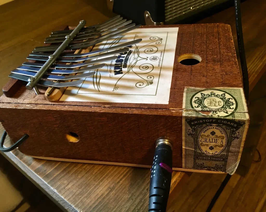 A lamellaphone, resembling an accordion, is resting on a wooden table.