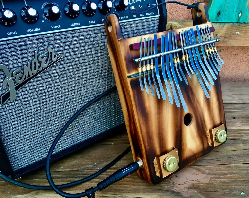 A wooden ukulele, a gourd instrument, is sitting next to a guitar amplifier.