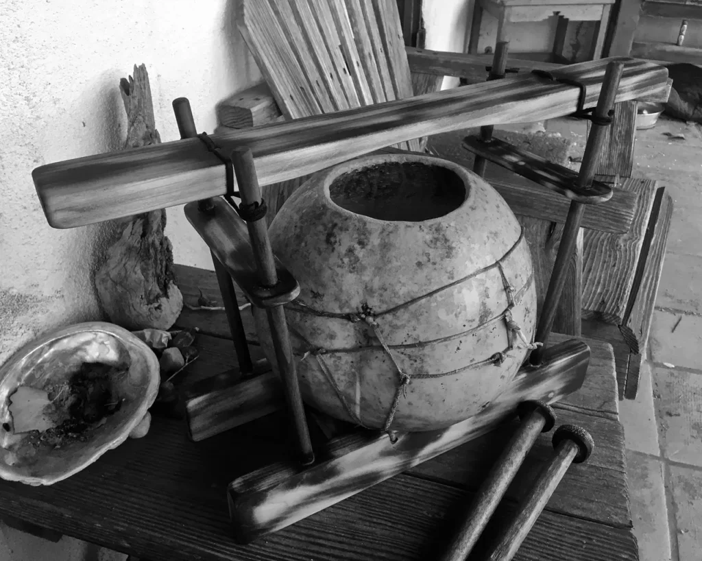 A black and white photo of a wooden bowl on a table.