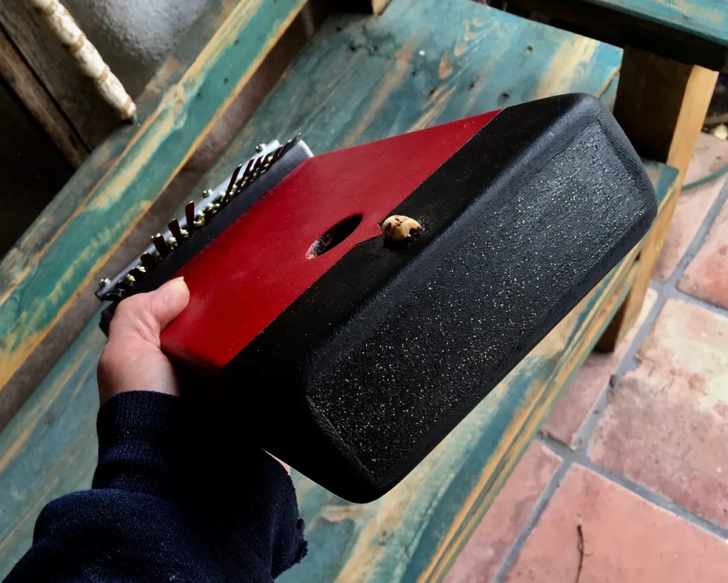 A person holding a red and black box filled with Ngoma music, a vibrant genre of African music.