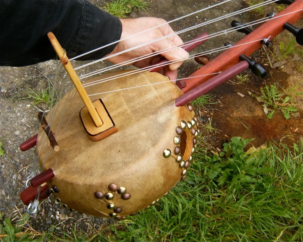 A person is holding an Ngoma instrument in the grass.