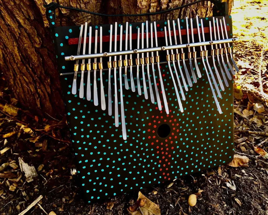 A wooden ukulele sitting on the ground next to a tree.