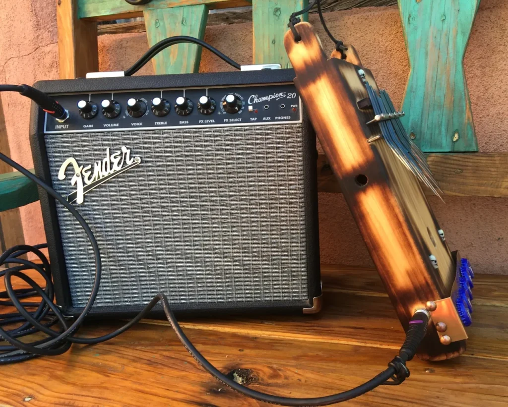 A fender amp sitting on a wooden bench, accompanied by a lamellaphone.