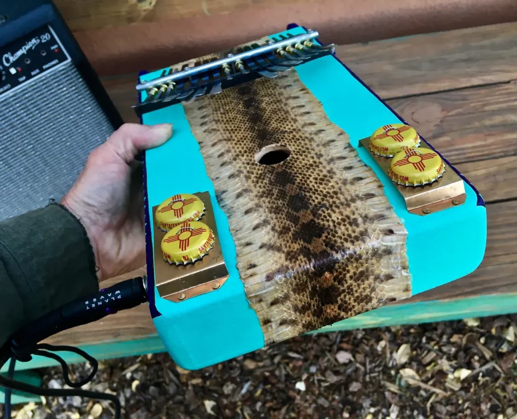 A person holding a gourd instrument with a snake on it.