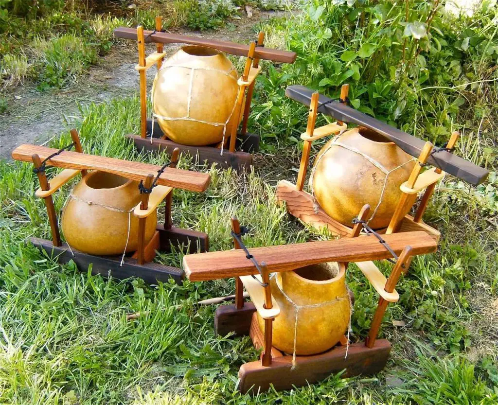 A group of wooden vases on a grassy field, featuring unique Gourd Instruments.