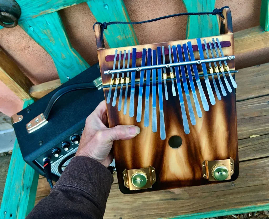 A person playing a gourd instrument on a wooden bench.