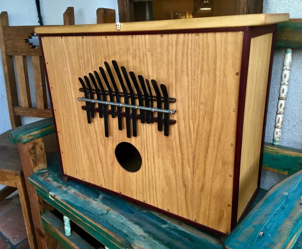 A wooden box, inspired by African drum aesthetics, sitting on top of a chair.