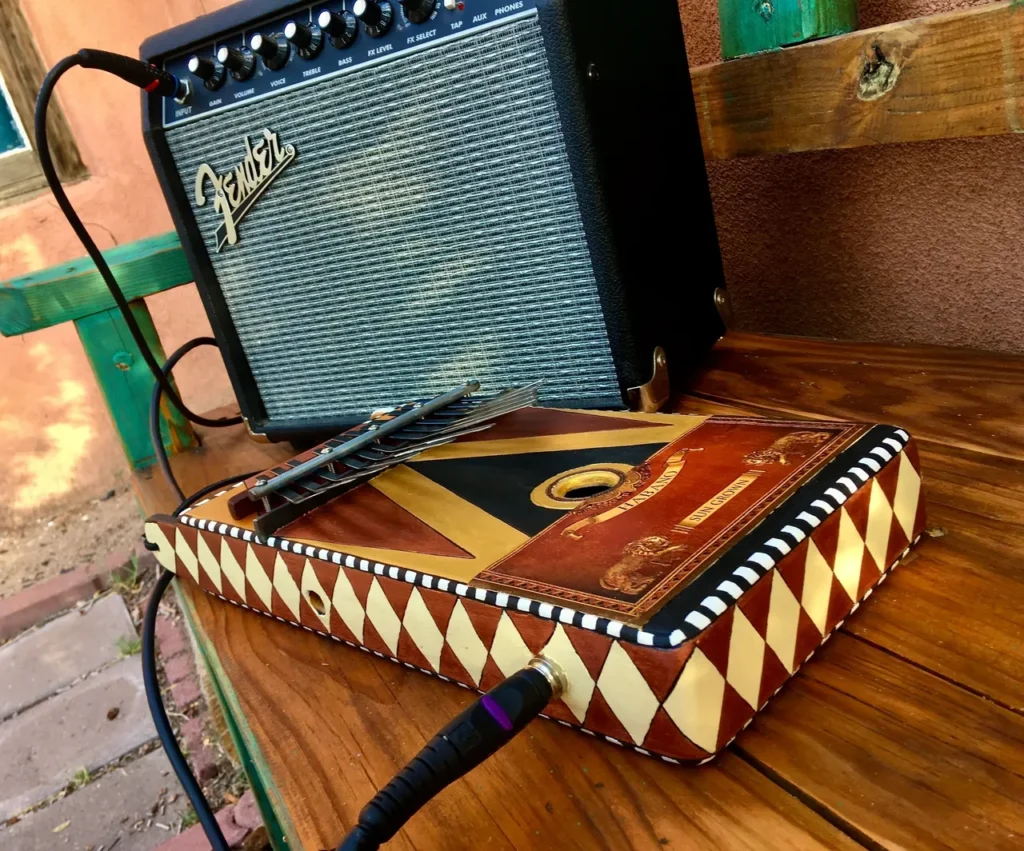 A gourd instrument sitting on a wooden bench, with an amplifier nearby.