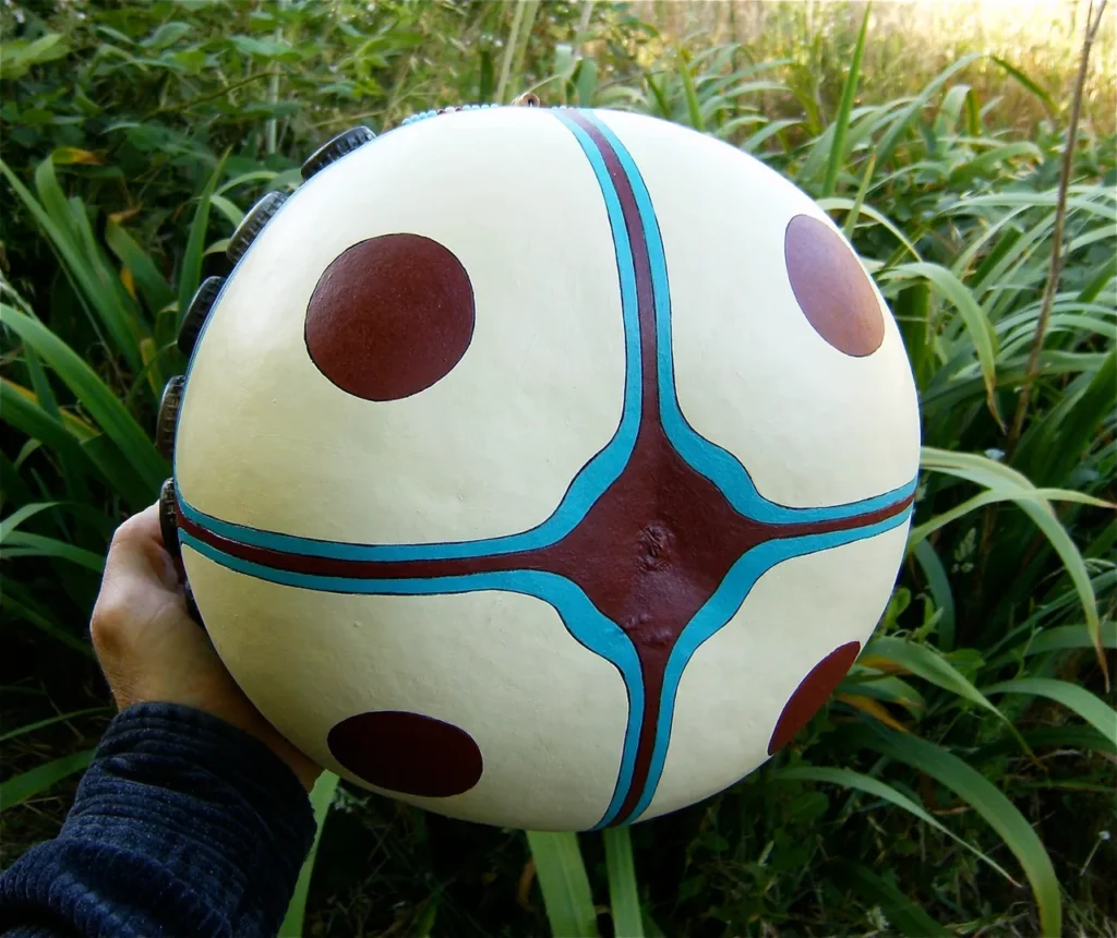 A person in Ngoma attire, holding a ball in the grass while surrounded by the vibrant and rhythmic sounds of African Music.