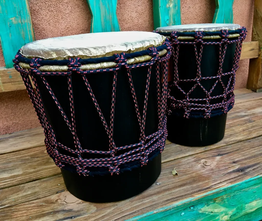 Two djembe drums, traditional African harps, sitting on a wooden bench.