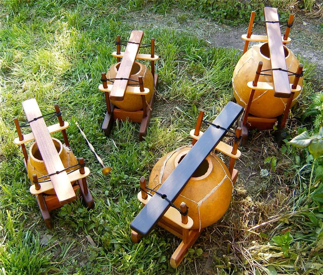 A group of wooden pots, resembling gourd instruments, sitting on the grass.