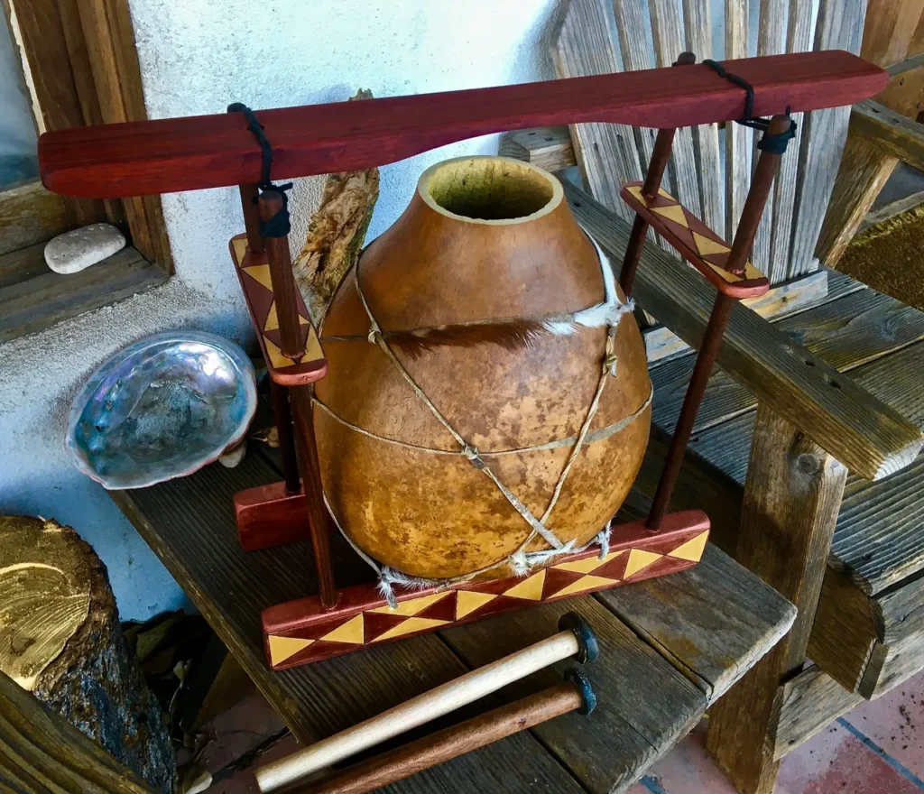 A wooden pot sitting on a wooden bench, transformed into a unique gourd instrument known as a lamellaphone.