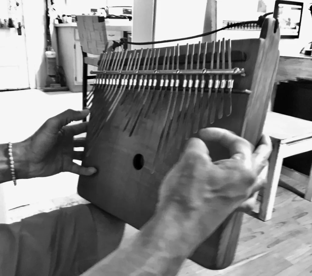 A man is playing a wooden marimbula.